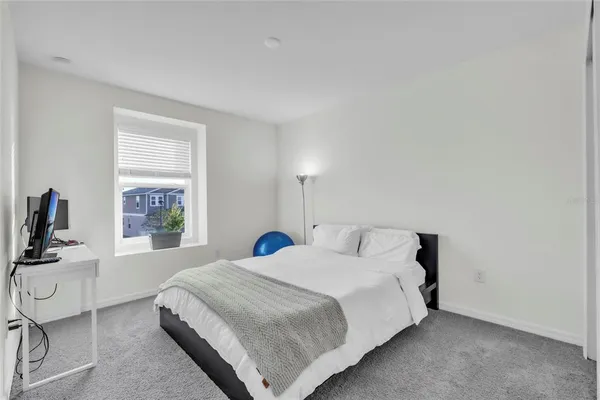 a bedroom with a bed a flat screen tv and windows