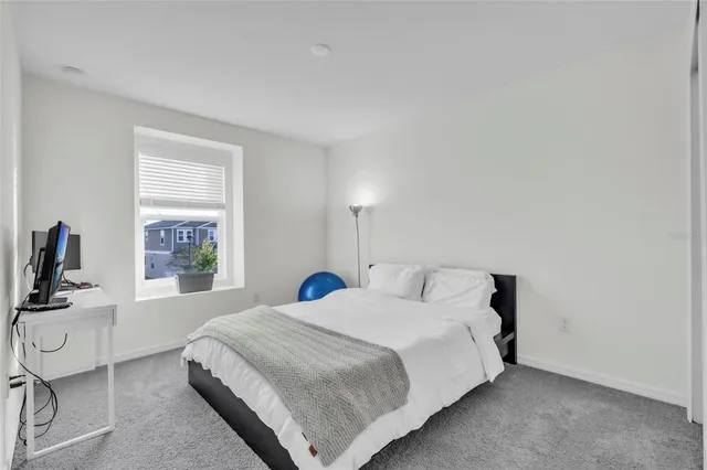 a bedroom with a bed a flat screen tv and windows