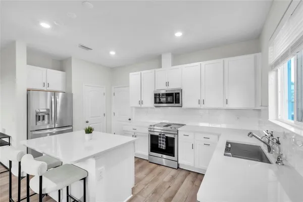 a kitchen with white cabinets and stainless steel appliances