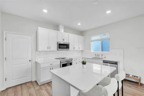 a kitchen with stainless steel appliances a microwave a sink and white cabinets