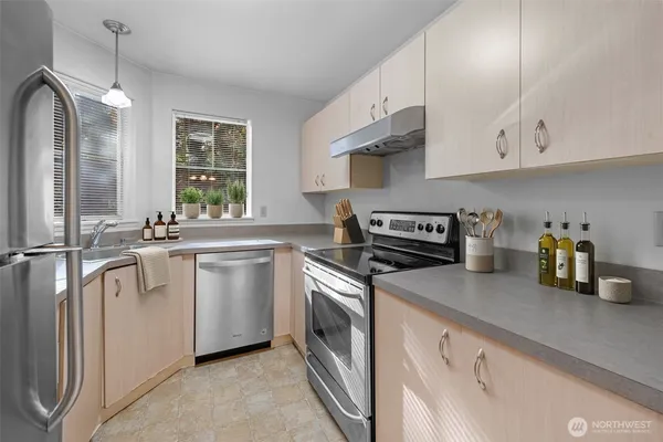 a kitchen with granite countertop stainless steel appliances a sink stove and cabinets