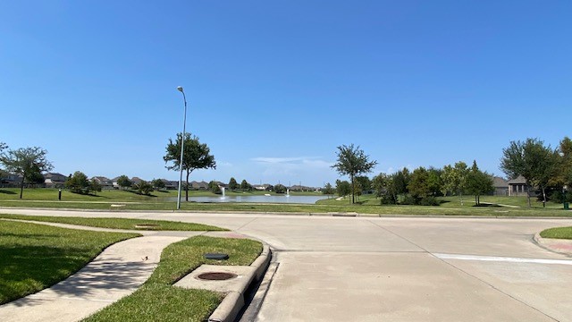 5002 Naples Grove Lane Rosharon, TX 77583 - Photo 38 of 38 Spacious neighborhood with well-maintained roads and a serene pond view, perfect for tranquil living.