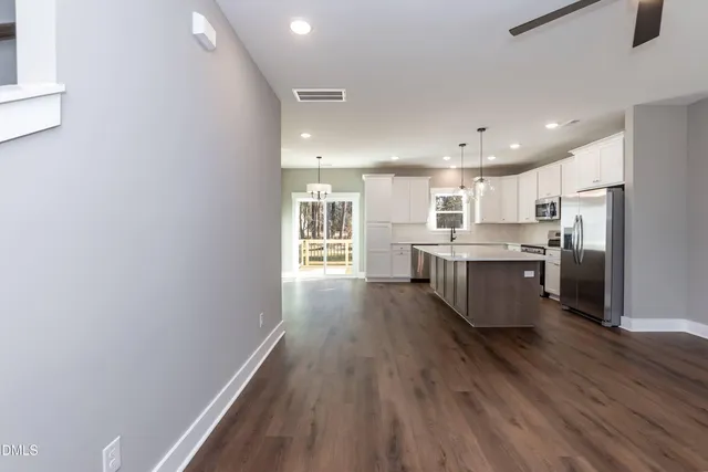 a view of an empty room with wooden floor and a ceiling fan