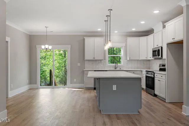 a kitchen with kitchen island granite countertop a stove a sink a center island and wooden floor