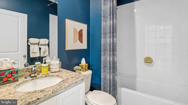 a bathroom with a granite countertop sink a toilet and shower
