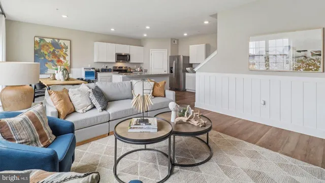 a living room with furniture kitchen view and a wooden floor