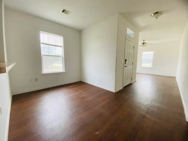 an empty room with wooden floor and windows