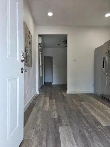 a view of a hallway with wooden floor and a refrigerator