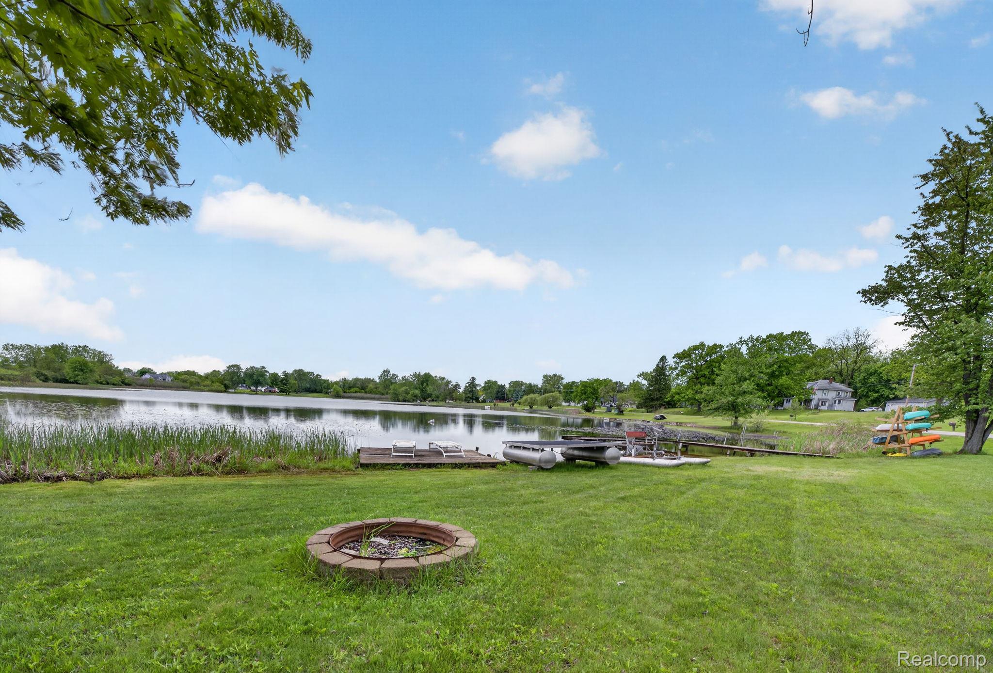 1280 Petts Road Fenton, MI 48430 - Photo 52 of 62 View of green lawn with an outdoor fire pit, a water view, and a floating dock