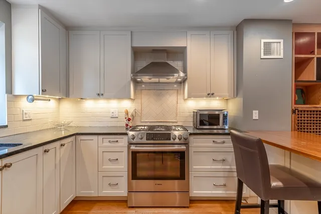 a kitchen with granite countertop a stove oven and white cabinets
