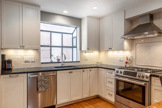 a kitchen with stainless steel appliances granite countertop a stove a sink and white cabinets