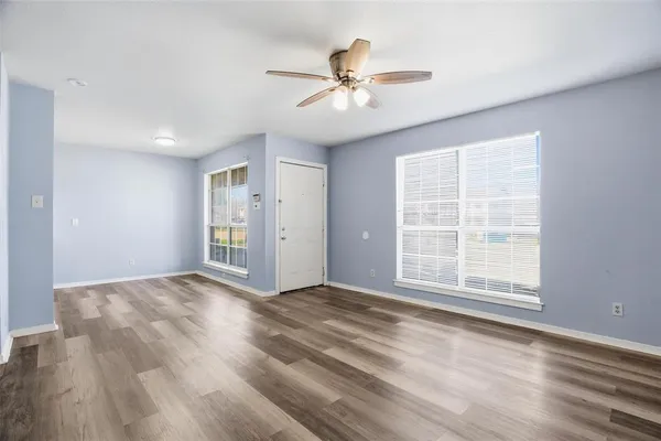 a view of an empty room with wooden floor and a window