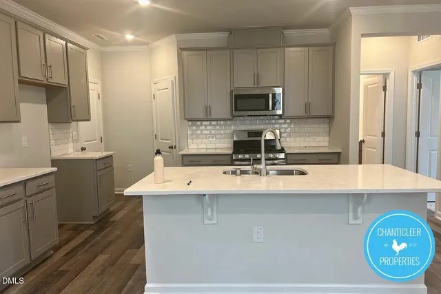 a kitchen with kitchen island granite countertop a sink a stove oven a counter top space and cabinets