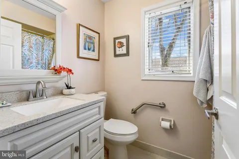 a bathroom with a granite countertop toilet sink and a window