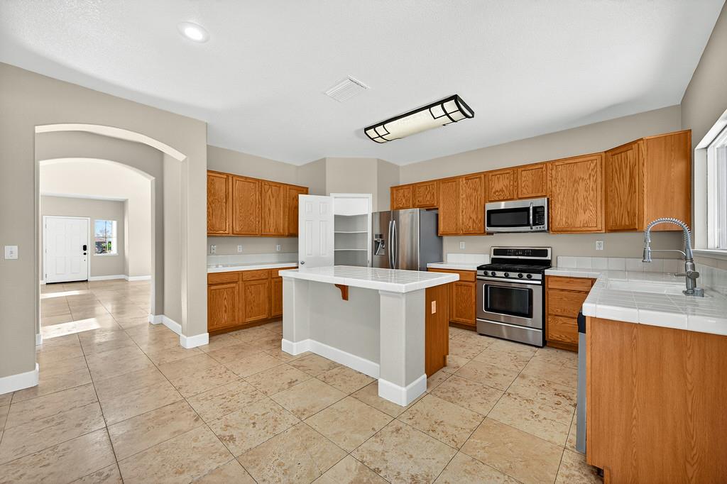 1619 7th Street Hughson, CA 95326 - Photo 9 of 61 a kitchen with stainless steel appliances granite countertop a stove top oven a sink dishwasher a dining table and chairs with wooden floor
