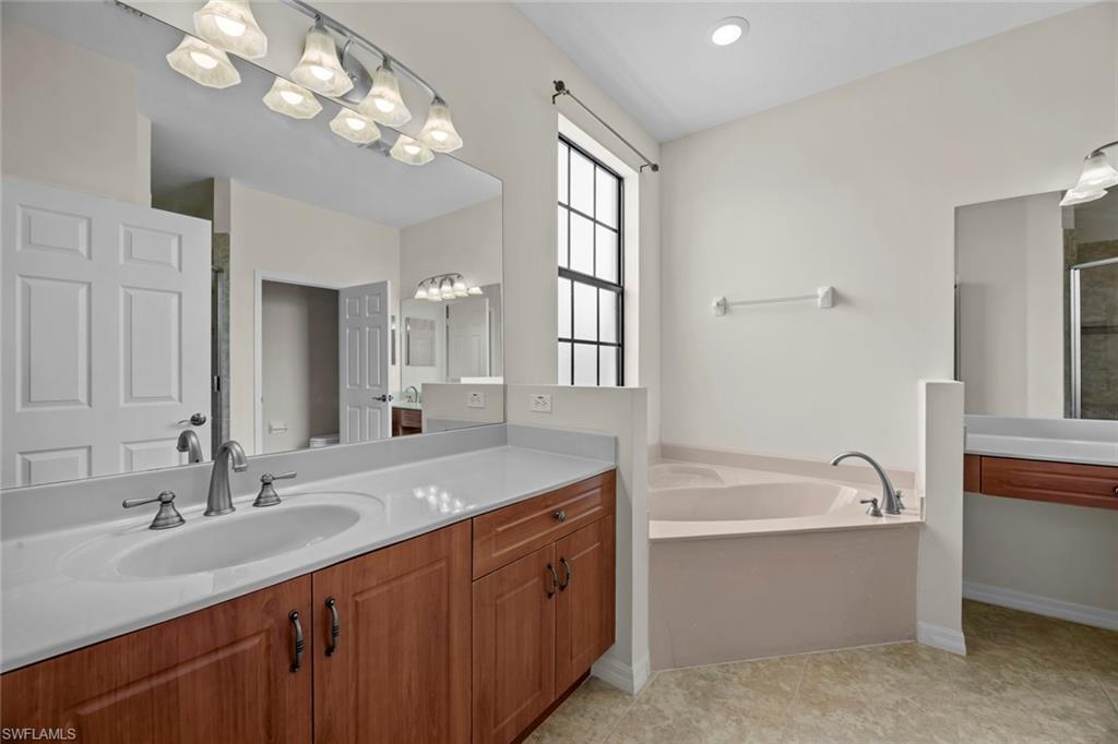 15594 Summit Pl Circle, Unit 402 Naples, FL 34119 - Photo 13 of 45 a bathroom with a granite countertop bathtub a sink and a large mirror