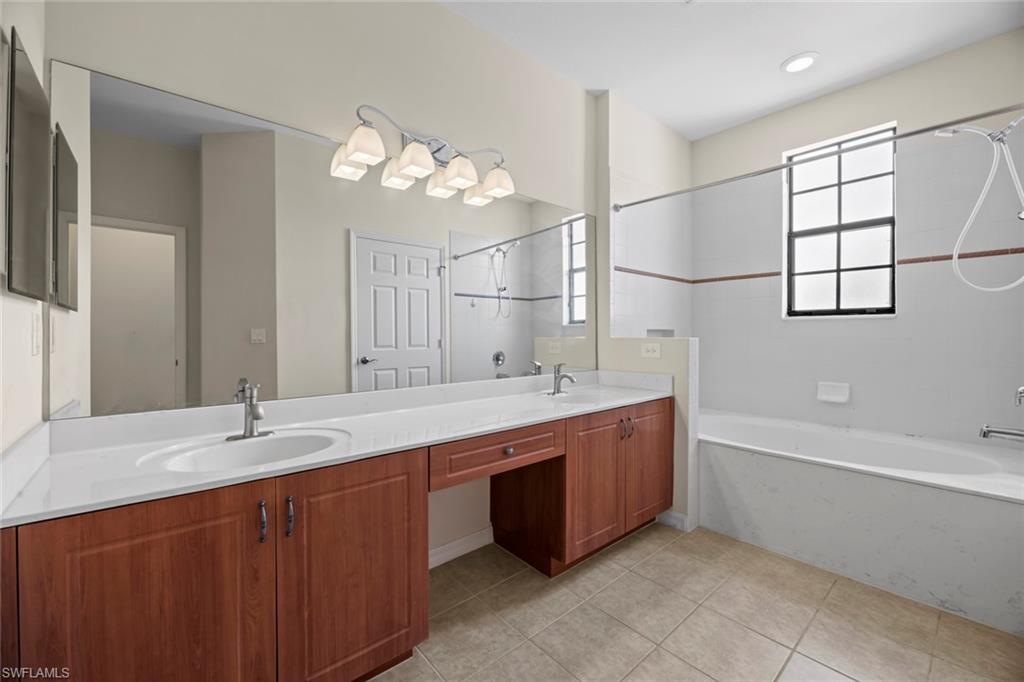 15594 Summit Pl Circle, Unit 402 Naples, FL 34119 - Photo 25 of 45 a bathroom with a tub a double vanity sink and a mirror