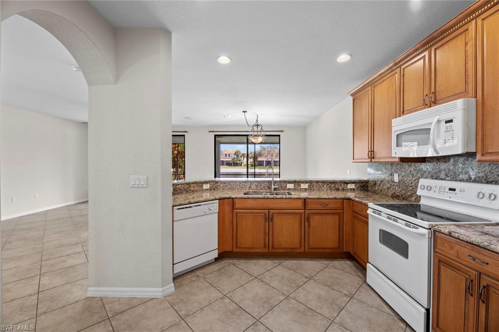 15594 Summit Pl Circle, Unit 402 Naples, FL 34119 - Photo 34 of 45 a kitchen with stainless steel appliances granite countertop a sink and stove top oven