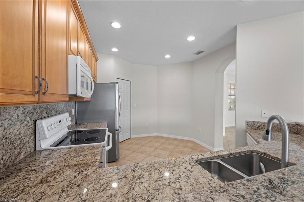 15594 Summit Pl Circle, Unit 402 Naples, FL 34119 - Photo 5 of 45 a kitchen with stainless steel appliances granite countertop a sink and a refrigerator