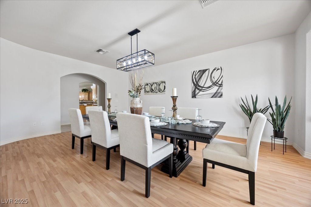 640 Quail Covey Road Henderson, NV 89002 - Photo 21 of 75 Formal Dining room with arched walkways, Pergo wood finished floors, and a chandelier
