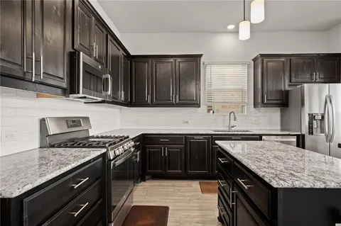 a kitchen with stainless steel appliances granite countertop a sink stove and refrigerator