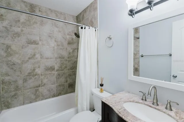a bathroom with a granite countertop bathtub shower sink and toilet