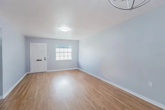 a view of an empty room with wooden floor and a window