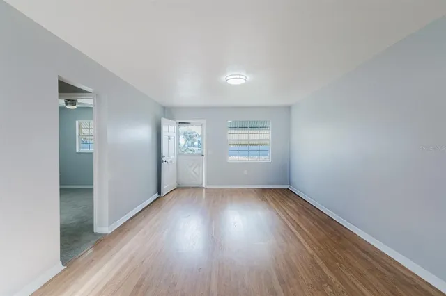 an empty room with wooden floor and windows