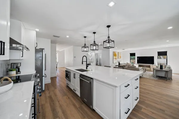 a large kitchen with stainless steel appliances a stove a sink dishwasher and a flat screen tv