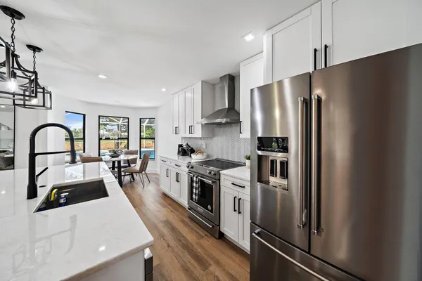 a kitchen with stainless steel appliances granite countertop a refrigerator a stove a sink and a stove