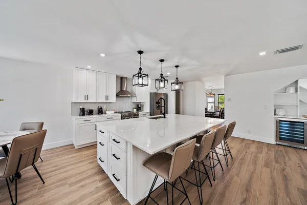 a large white kitchen with wooden floor and stainless steel appliances