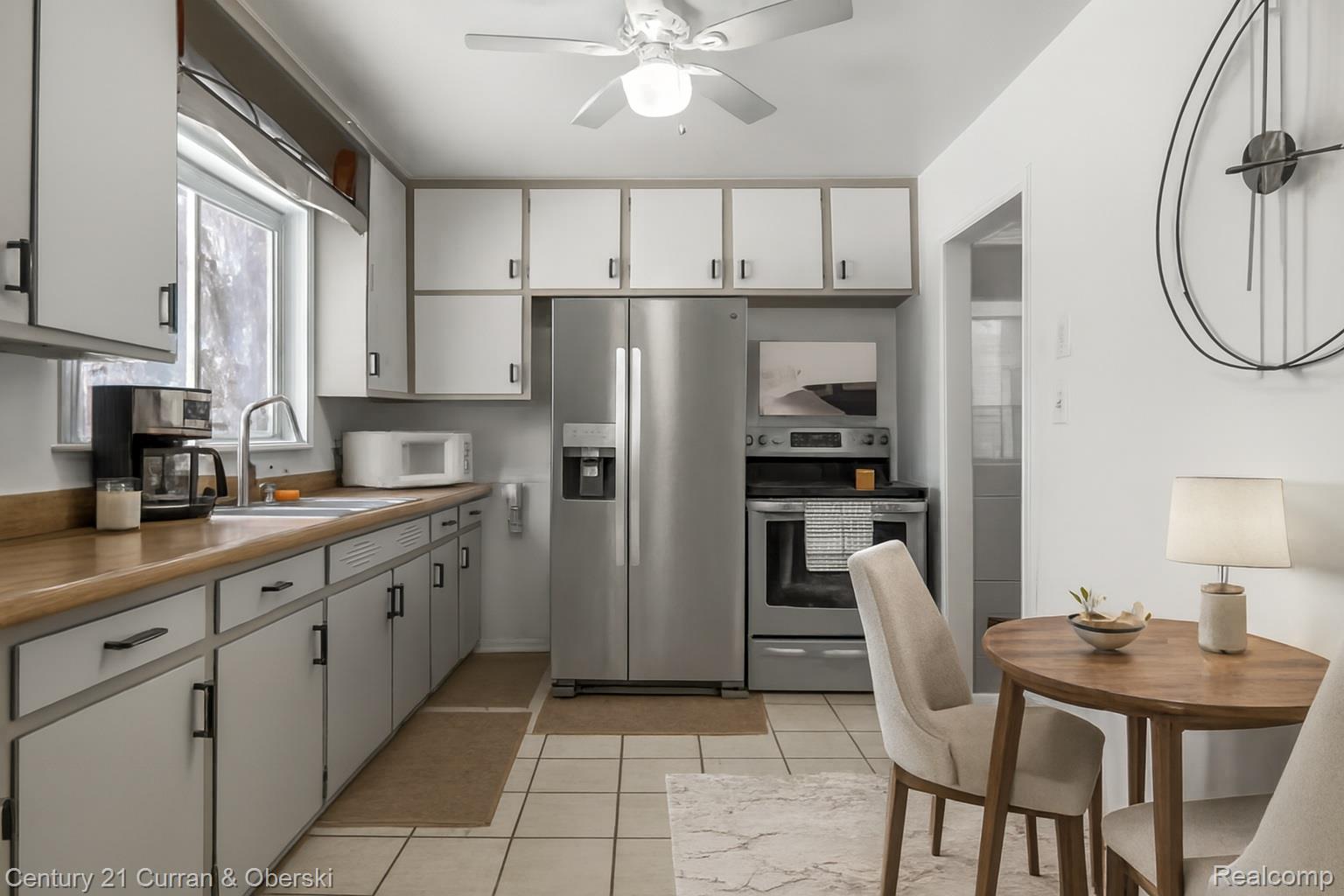 22327 Wick Road Taylor, MI 48180 - Photo 3 of 10 Kitchen featuring appliances with stainless steel finishes, ceiling fan, white cabinetry, light tile patterned flooring, and light countertops