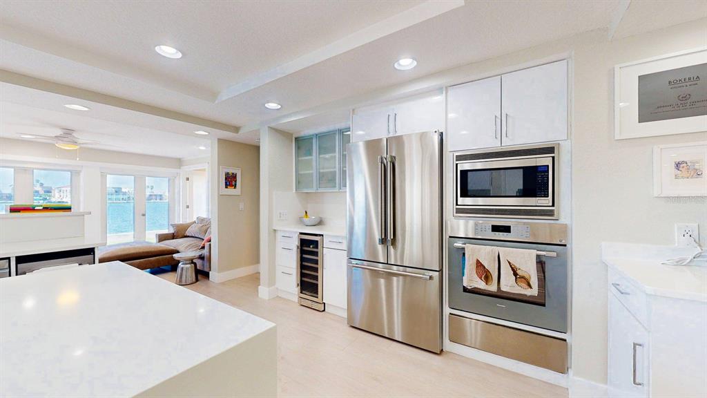 509 55th Avenue St. Pete Beach, FL 33706 - Photo 26 of 63 a kitchen with stainless steel appliances a refrigerator a stove a sink a oven with white cabinets and wooden floor