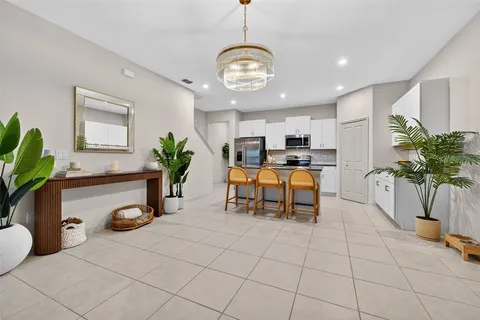 a kitchen with stainless steel appliances granite countertop a refrigerator a stove a sink a dining table and chairs with wooden floor