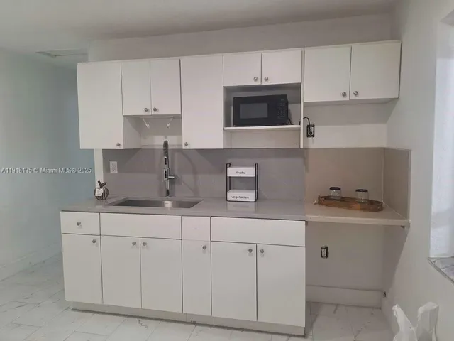 a kitchen with white cabinets and sink
