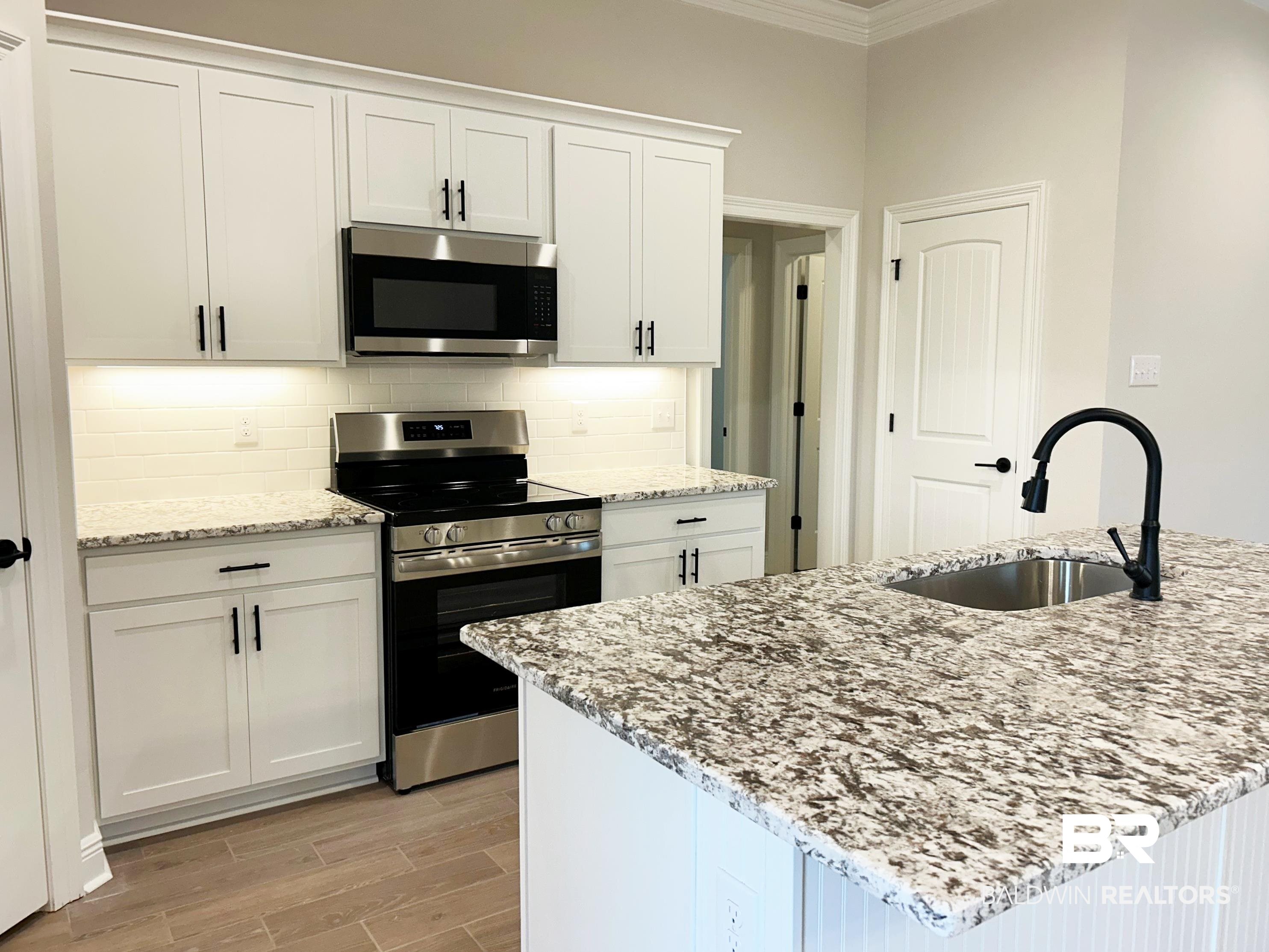 873 Sumter Loop Foley, AL 36535 - Photo 8 of 26 Kitchen featuring stainless steel appliances, light stone counters, white cabinetry, and crown molding