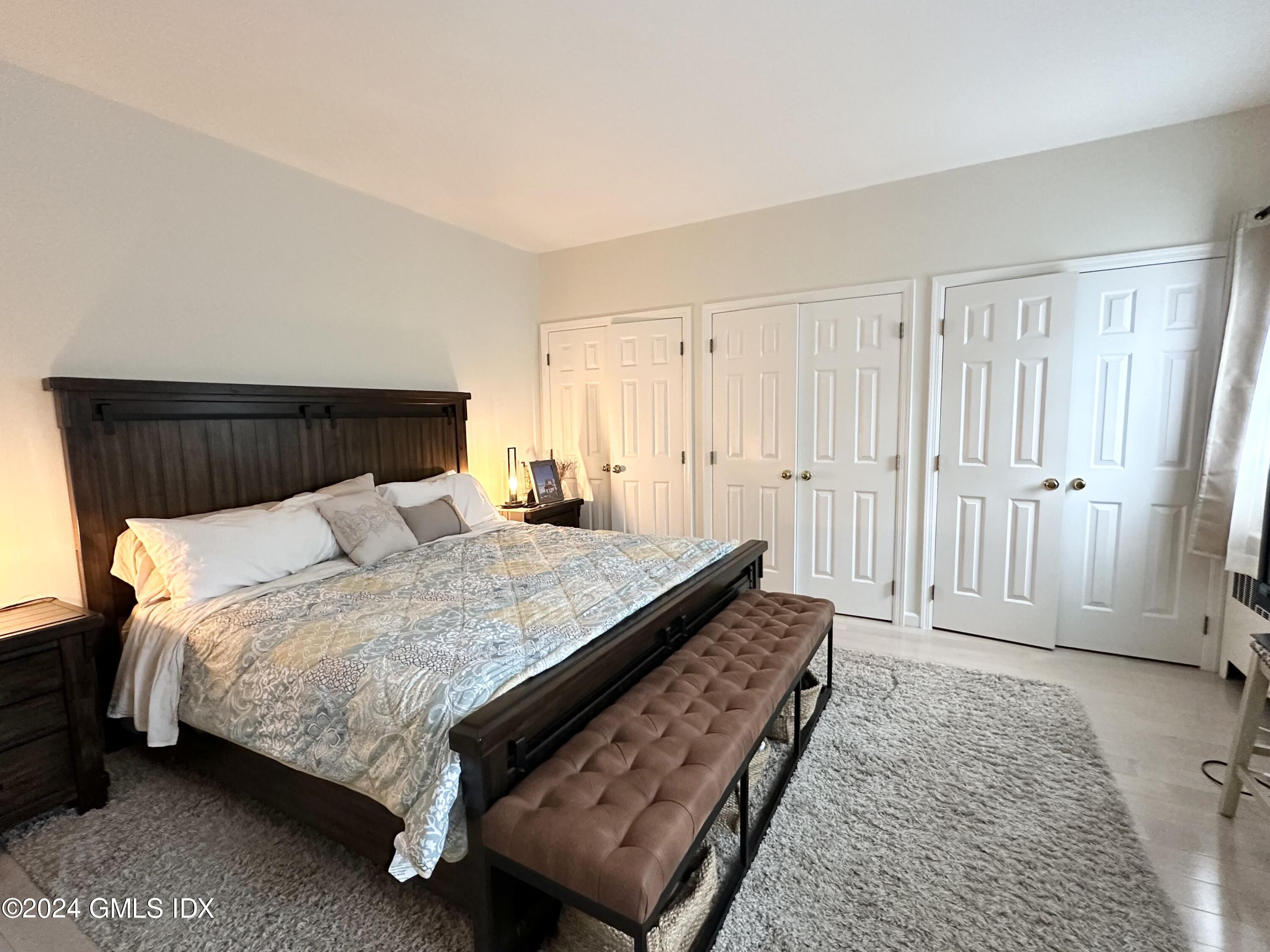 14 Byram Shore Road, Unit 1 Greenwich, CT 06830 - Photo 9 of 19 a large bed sitting in a bedroom next to a cabinet