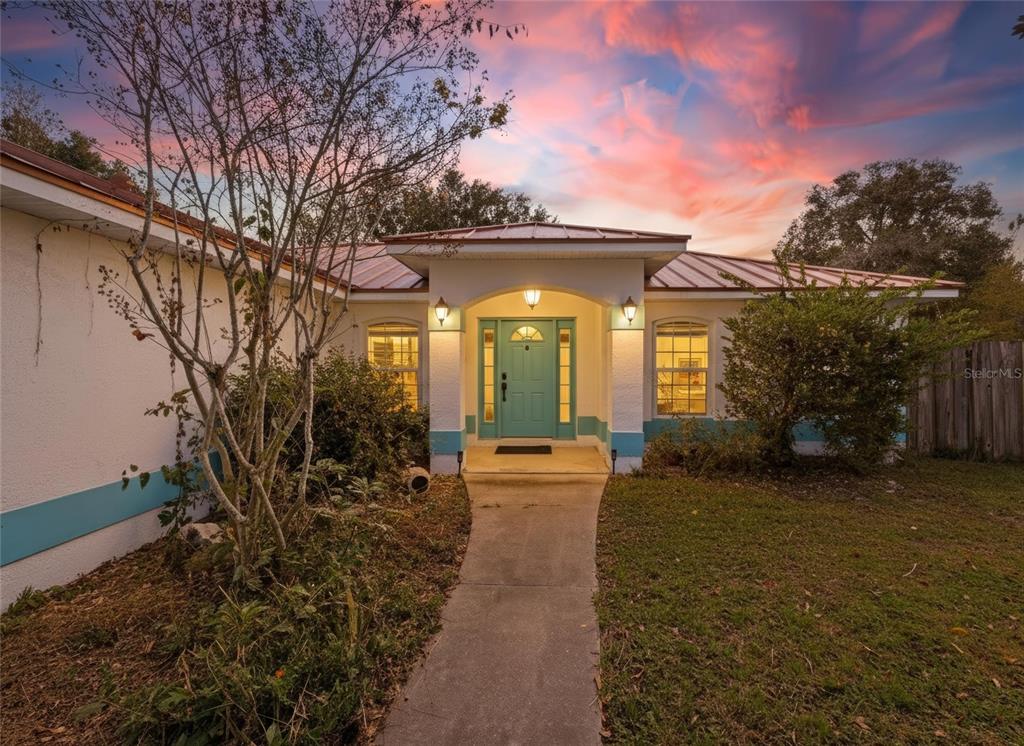 a view of a house with large trees and plants