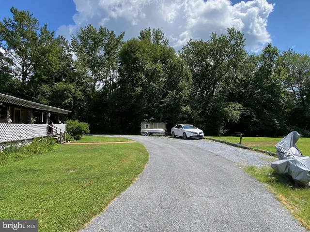 a backyard of a house with table and chairs plants and large trees