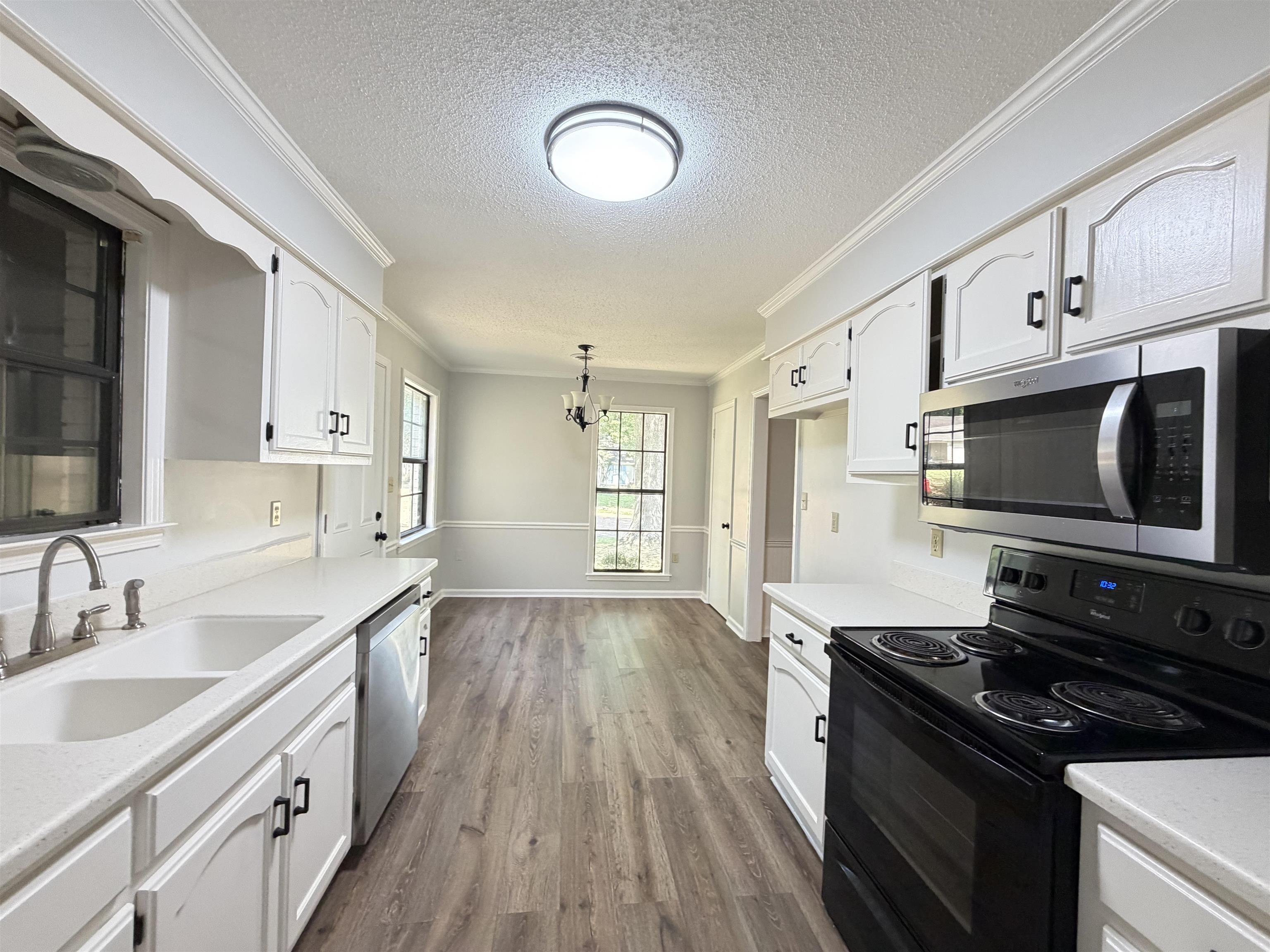 388 Park Hill Road Collierville, TN 38017 - Photo 5 of 19 Kitchen featuring white cabinetry with black hardware, white countertops, wood-finish flooring, and stainless steel appliances including a microwave and dishwasher