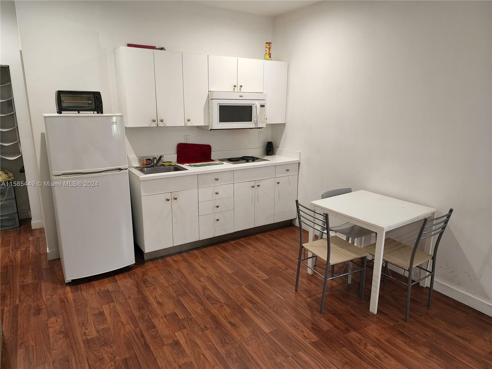 a white kitchen with wooden floors and white appliances