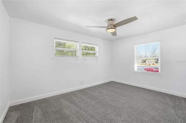 an empty room with windows and ceiling fan