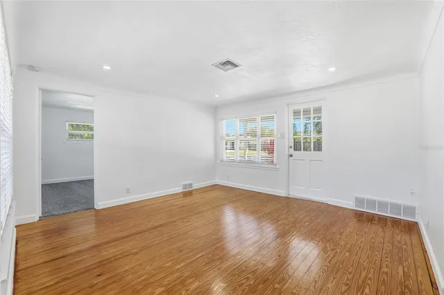 an empty room with wooden floor and windows