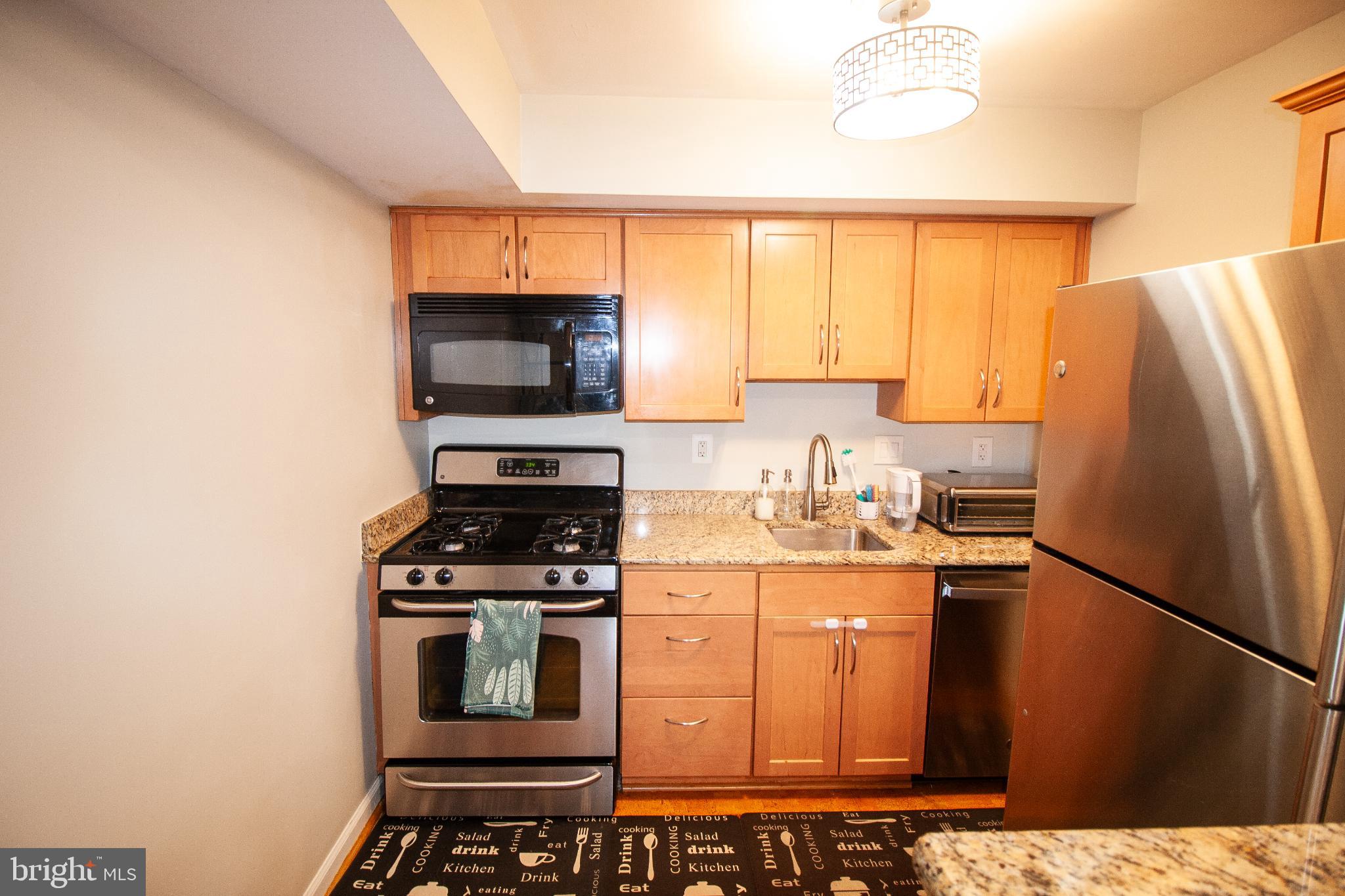 7548 Spring Lake Drive, Unit A Bethesda, MD 20817 - Photo 7 of 23 a kitchen with stainless steel appliances a stove a microwave and a refrigerator