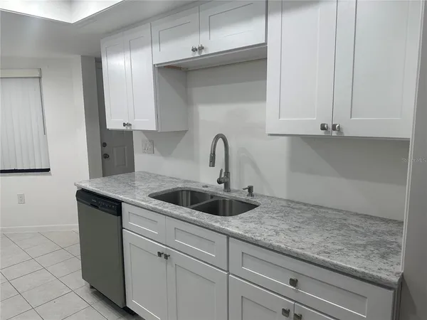 a kitchen with granite countertop white cabinets and a sink