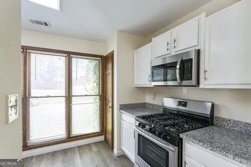 a kitchen with white cabinets and appliances