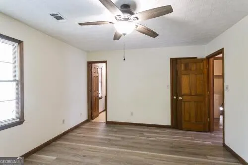 an empty room with wooden floor fan and windows
