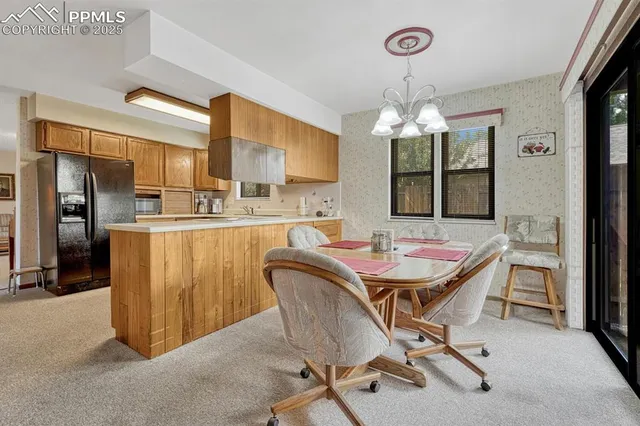 a dining room with stainless steel appliances a table chairs and chandelier