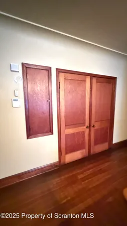 a view of a hardwood floor in a hall with a window