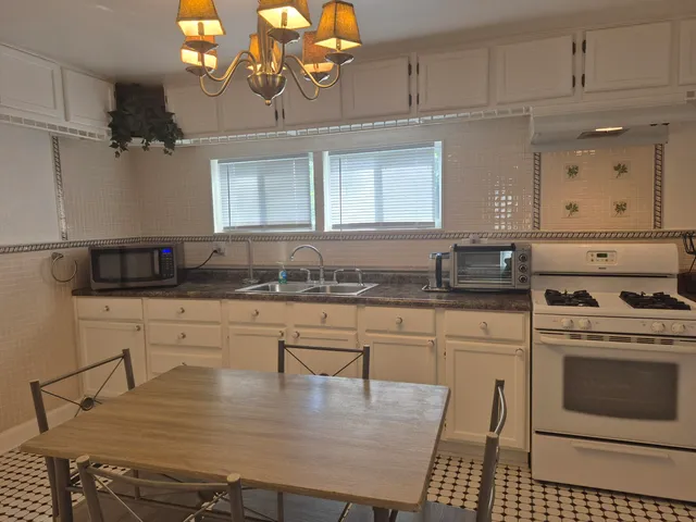 a kitchen with stainless steel appliances granite countertop a stove a sink dishwasher and cabinets with wooden floor